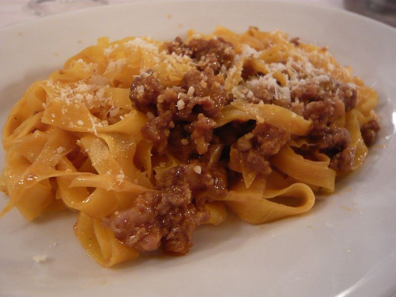 Prato fundo de tagliatelle cobertos de ragù de carne e parmesão ralado.